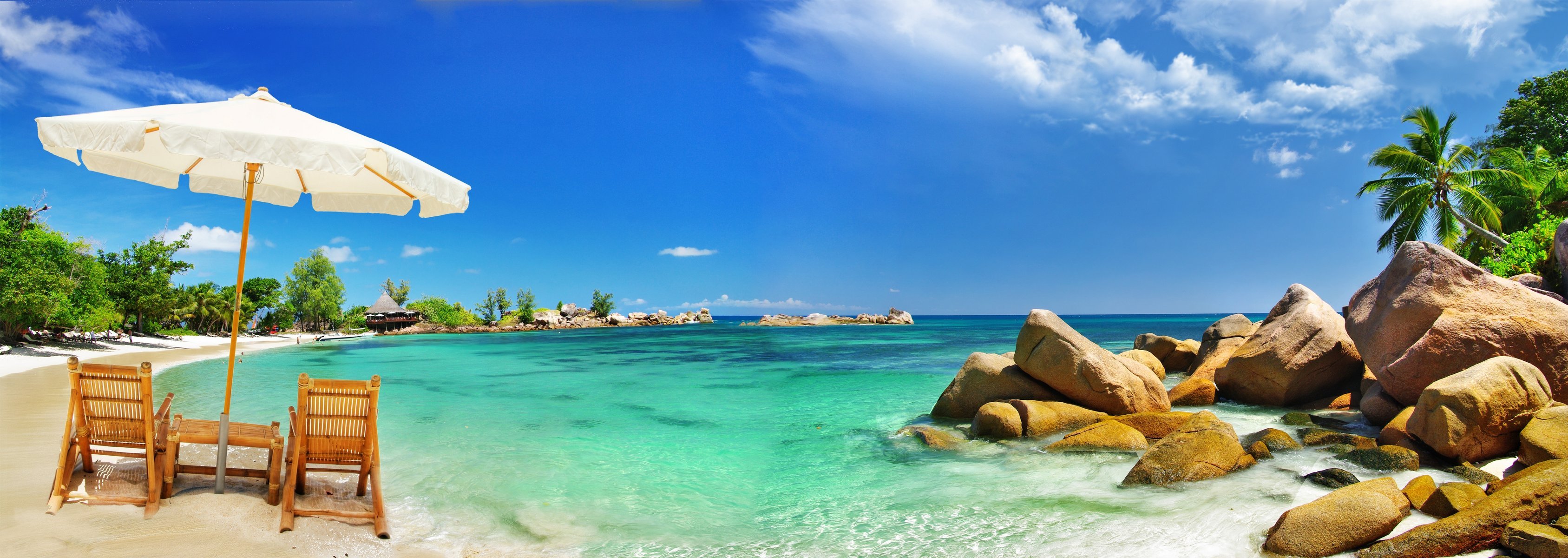 costa mar playa arena piedras palmeras trópicos paraguas sillas paraguas