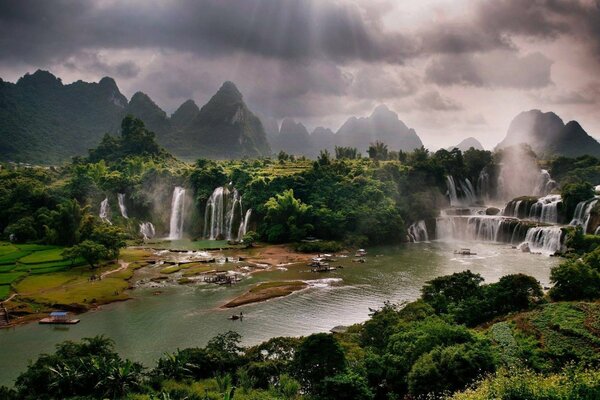 Landscape with a pond and waterfalls under the rays of the sun through the clouds