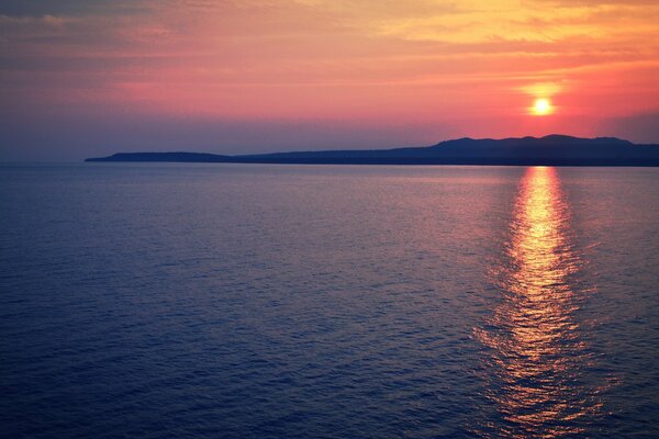 An island in the sea on the background of sunset