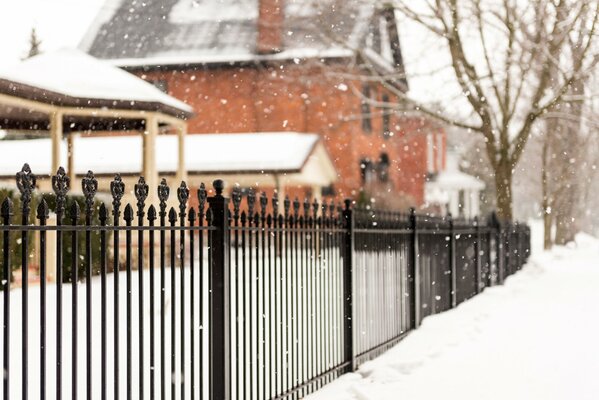 Casa invernale dietro una recinzione in ferro battuto