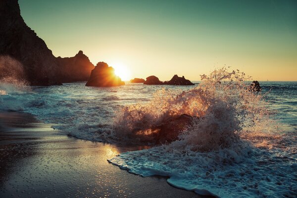 Salpicaduras de olas en la playa al atardecer