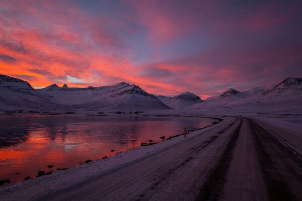 Route d hiver le long du lac sur fond de coucher de soleil