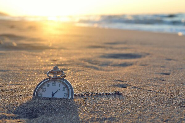 Helle Sonne am Ufer. Uhr im Sand