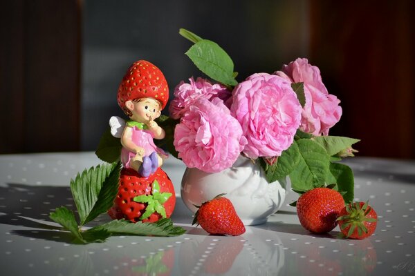 Pink flowers in a white vase next to strawberries