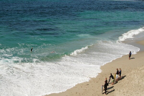 Люди на песочном пляже. Морские волны