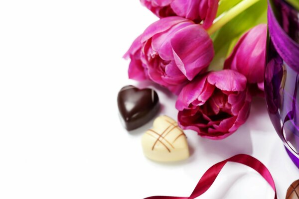 Zwei Pralinen und rosa Tulpen