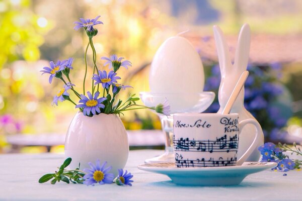 Still life with a vase with cornflowers, a cup of tea and a porcelain rabbit