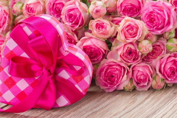 Geschenk aus einer Schachtel mit Herzen und rosa Rosen