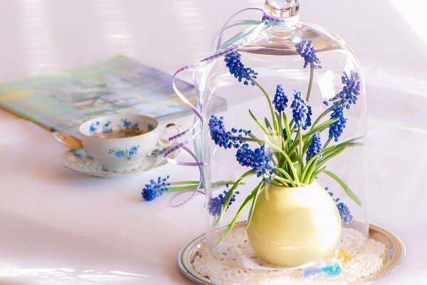 A cup of tea and a bouquet of flowers in a glass flask