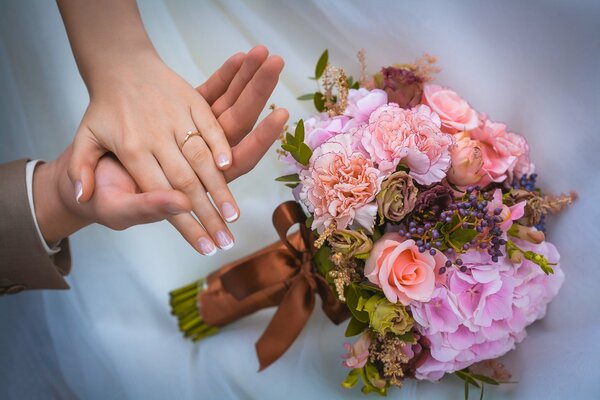 Mains de jeunes mariés et bouquet de mariage