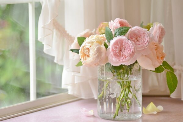 Die Rosen sind zart rosa in einer Glasvase