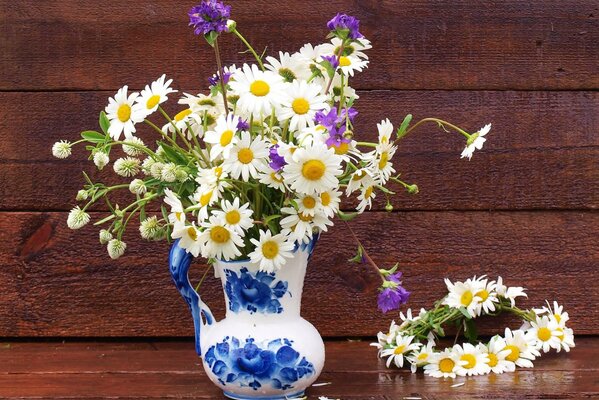 Stillleben mit Gänseblümchen in einem Krug und einem Kranz