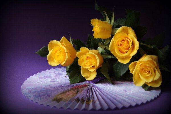 A bouquet of five yellow roses and a Japanese fan