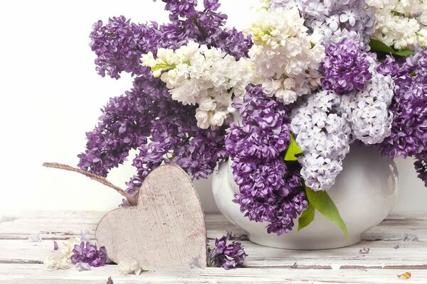 Lilas de mai dans un vase et un coeur en bois