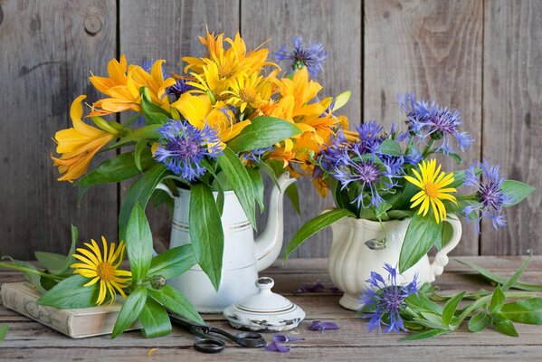 Bouquet de lys et de bleuets sur la table avec des ciseaux et un livre