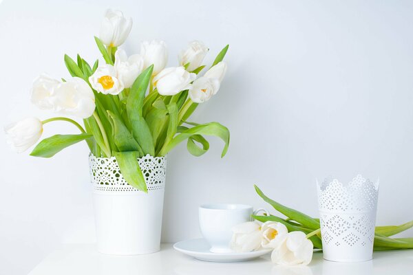 Białe tulipany w wazonie i filiżance herbaty