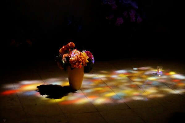 A vase of flowers on the floor. A bright bouquet. Poor lighting