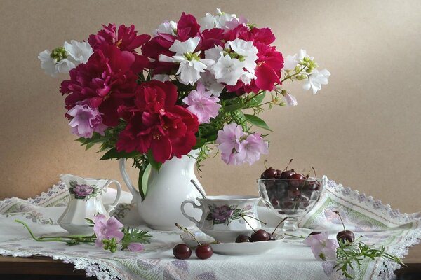 Ripe cherries and a vase of flowers