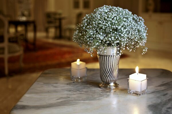 Candles and a vase with an airy bouquet are on the table