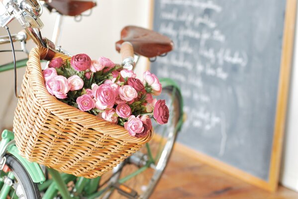 Fahrrad mit einem Blumenstrauß aus rosa Blüten im Korb