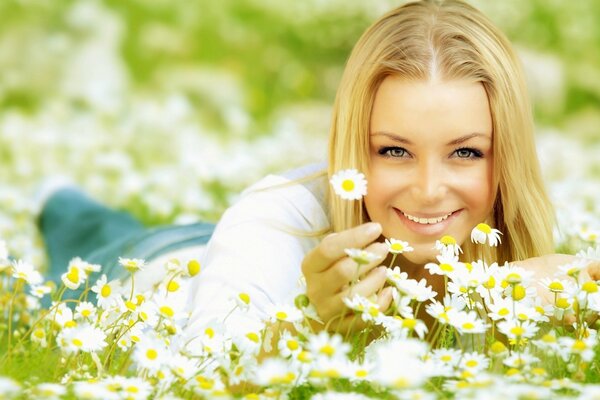 Chica rubia en el campo con margaritas sonriendo