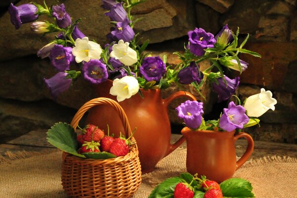 Stillleben Blumenstrauß in einem Krug Glocken in einem Korb mit Erdbeeren