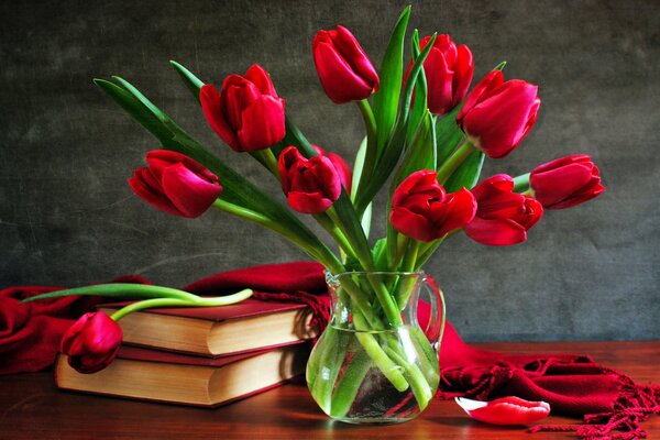 Красные тюльпаны в вазе на столе с книгами