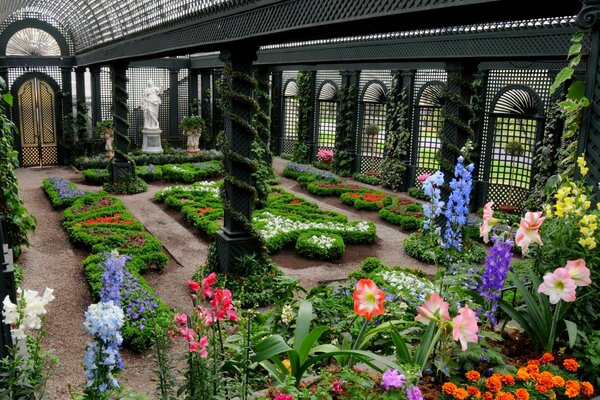 Belle serre avec des statues et des parterres de fleurs