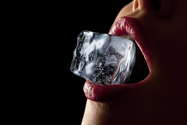 A piece of ice clamped in a sexy girl s mouth