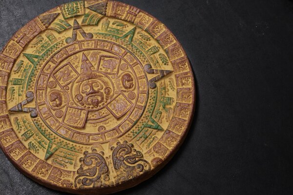 Calendario Azteca o símbolos inusuales en un emblema redondo sobre un fondo negro