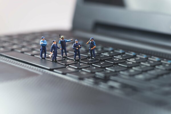 Small figures of dolls stand on a laptop