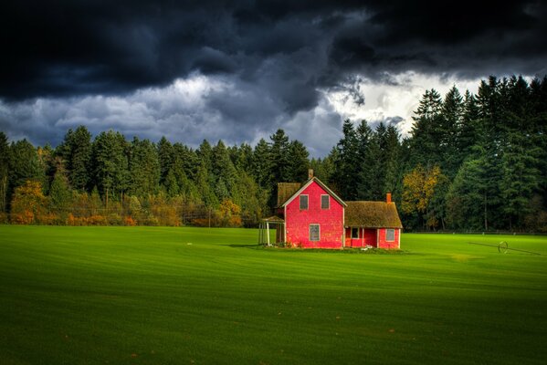 Rotes Po-Haus inmitten eines grünen Feldes mit dunklem Himmel