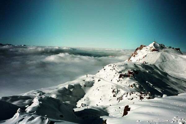 Crête enneigée de hautes montagnes au-dessus des nuages