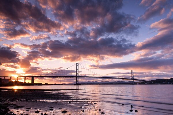 Pont sur fond de coucher de soleil. Rivière tranquille. Nuages