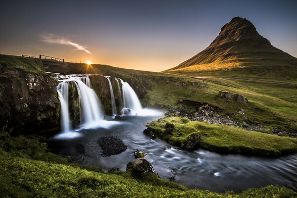 Cascata con il fiume sullo sfondo di una montagna solitaria