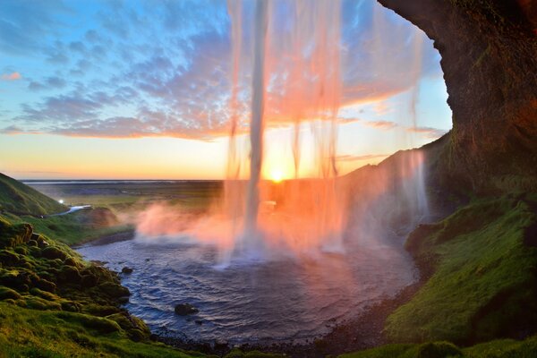 Cascata che cade sullo sfondo del tramonto. Islanda