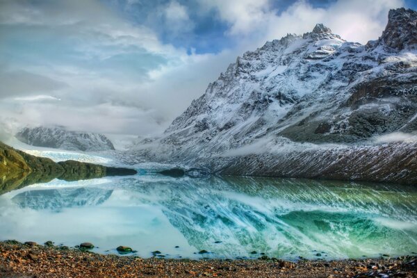 Lago de montaña transparente, rocas cubiertas de nieve