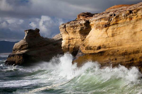 Vagues de la mer mousseuse battant sur les rochers de la falaise