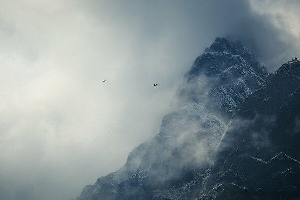 Montagne Dell Himalaya nella neve con uccelli volanti tra le nuvole