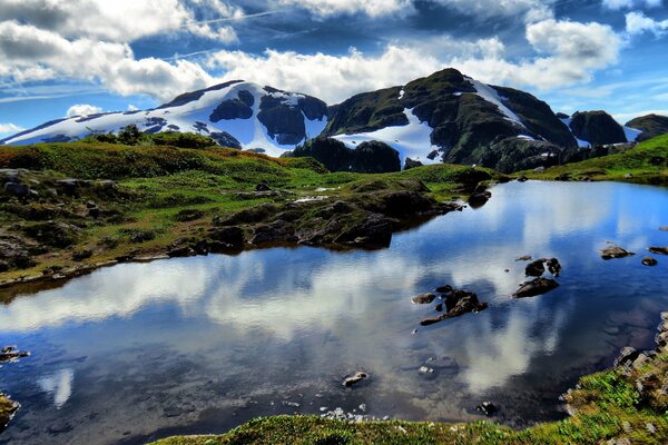 Les nuages se reflètent dans le lac au pied des montagnes