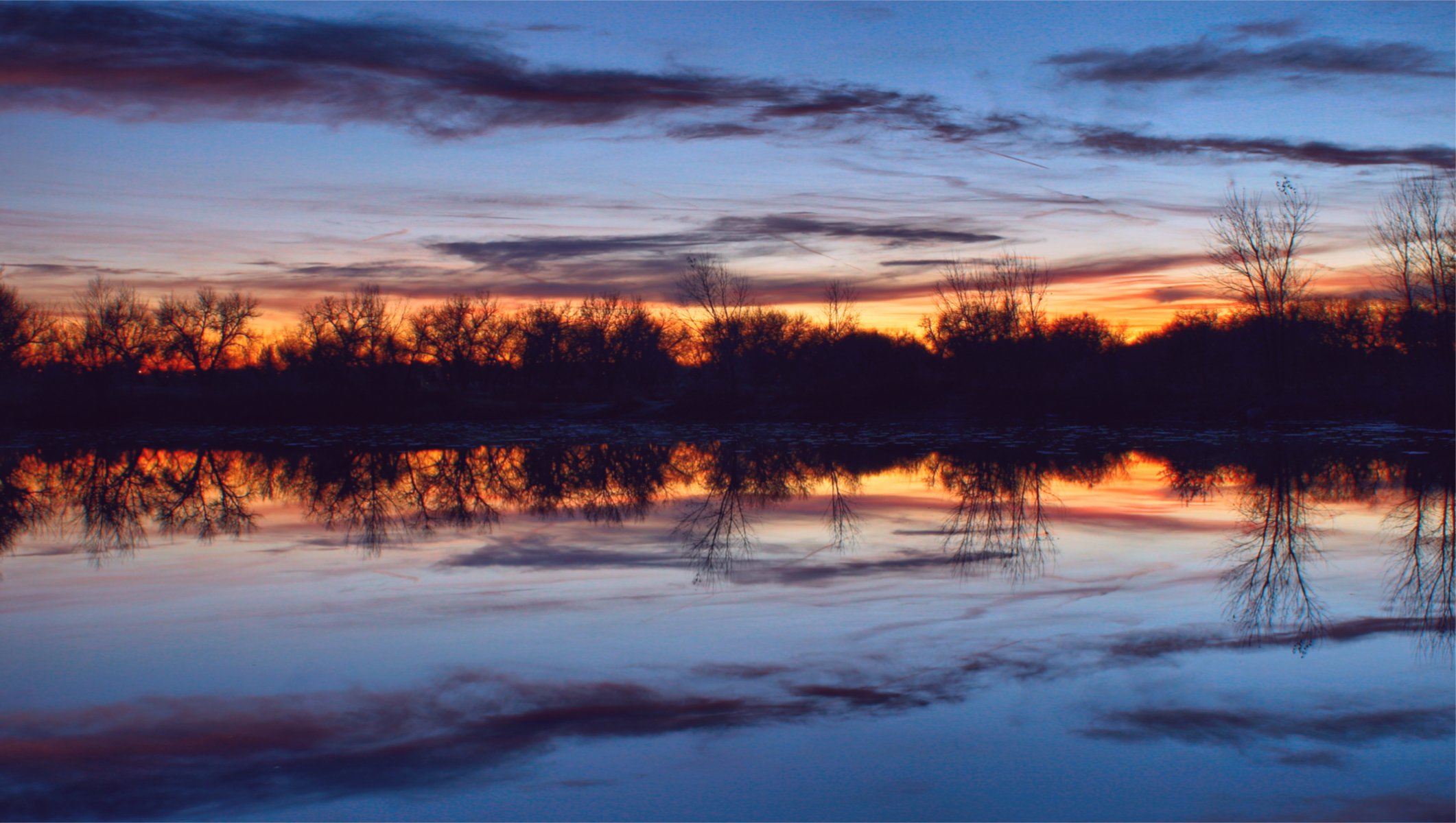 sera crepuscolo arancione tramonto blu cielo nuvole alberi fiume acqua superficie liscia silenzio riflessione