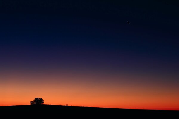 Puesta de sol roja. Luna en el cielo nocturno