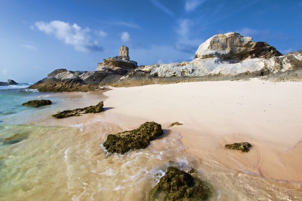 Spiaggia di pietra vicino al mare. Cielo sereno sullo sfondo delle rocce. Costa rocciosa di pietra. Acqua pura