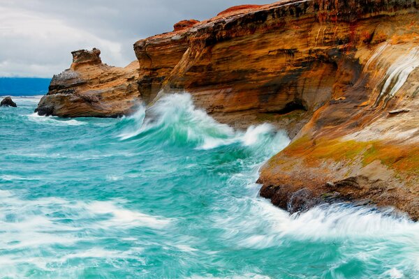 Las olas azules golpean las rocas rojas