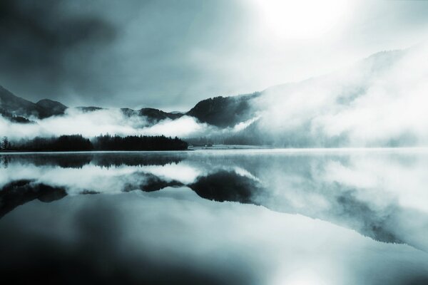 Misty surface. Reflection of mountains and forests in water