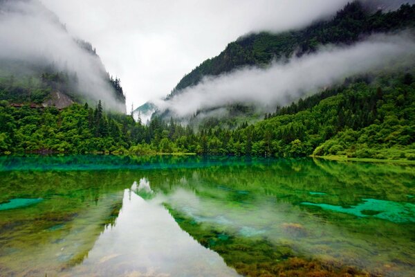 The mirror surface of the lake reflecting the green hills