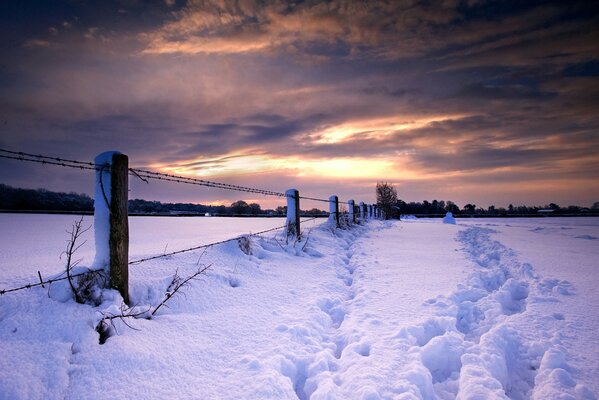 Winter verschneite Landschaft, Spuren auf Schnee entlang des Zauns