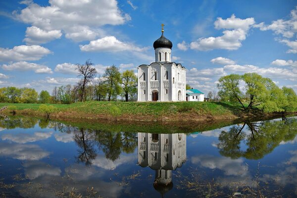 Weiße Kirche mit blauer Kuppel am Ufer des blauen Sees