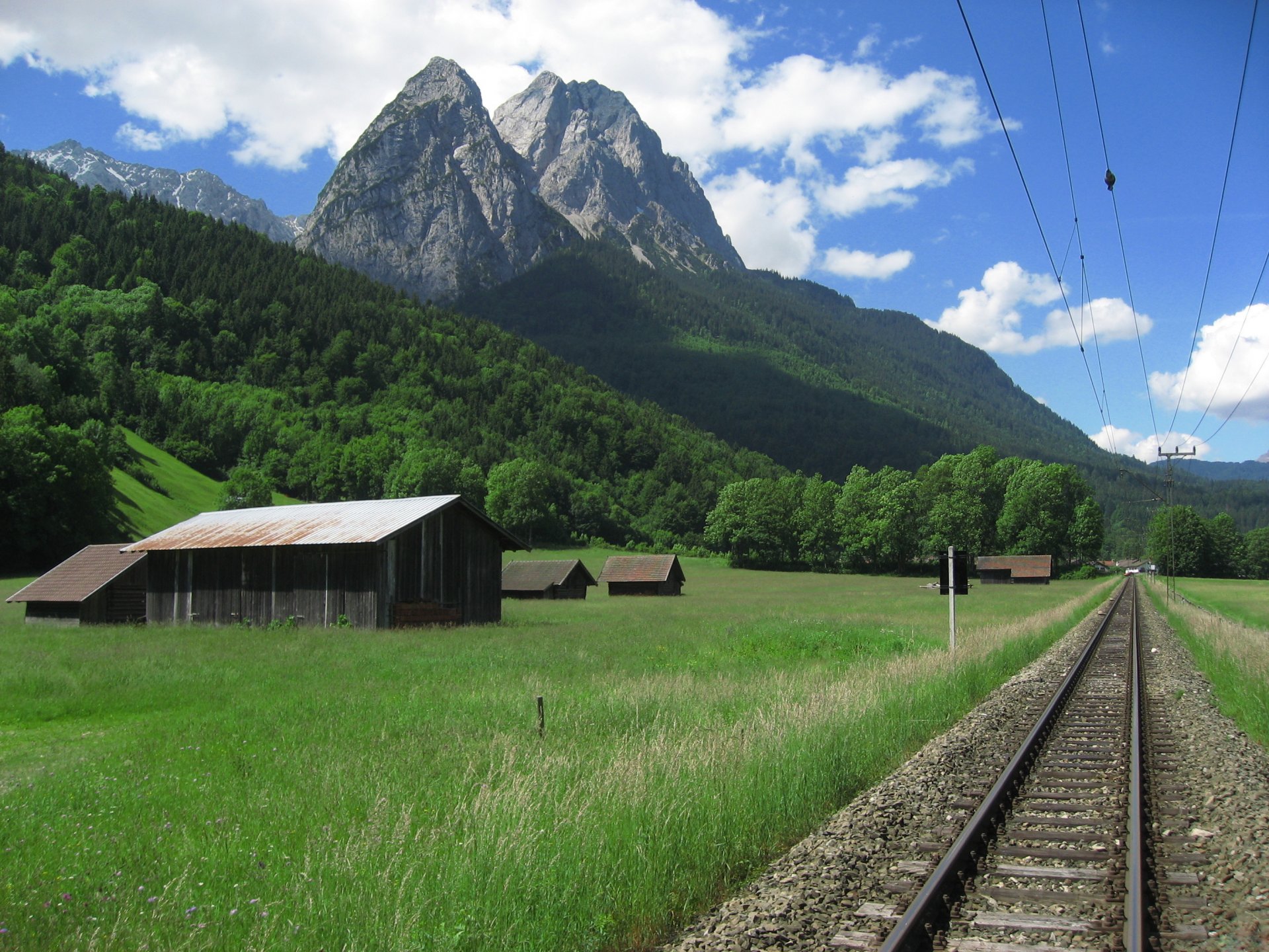 chemin de fer chemin rails fils montagnes vallée ciel nuages nature photo sommet pic montagne paysage maison clairière herbe forêt arbres