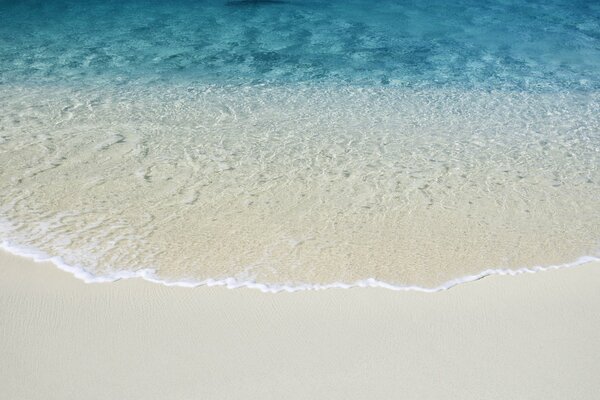 Sand am Strand mit klarem Wasser